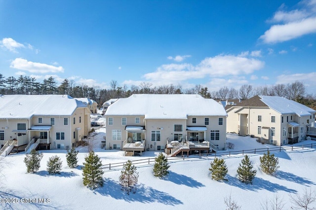 snow covered rear of property with a residential view, fence, and a deck