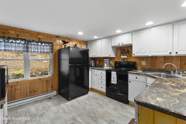 kitchen featuring black appliances, wood walls, sink, a baseboard radiator, and white cabinets