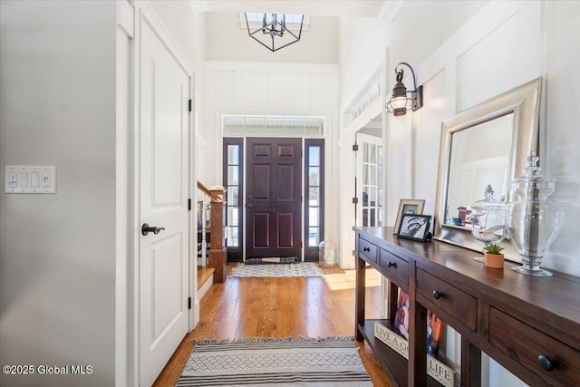 entryway featuring a notable chandelier, a decorative wall, and light wood-style flooring