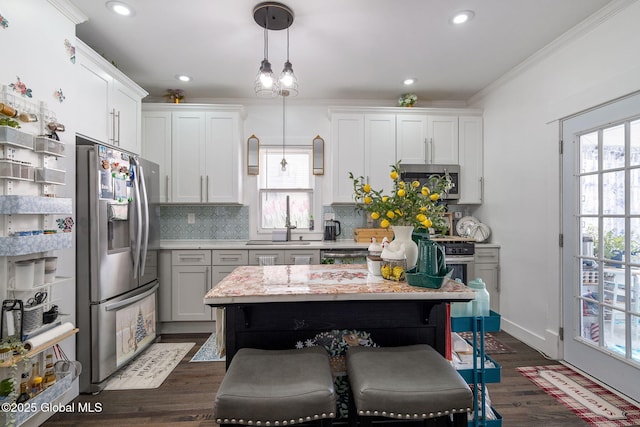 kitchen featuring stainless steel appliances, white cabinetry, a kitchen breakfast bar, decorative backsplash, and decorative light fixtures