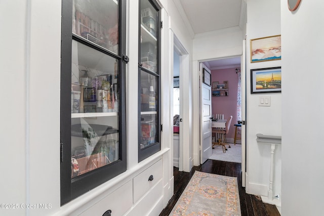 corridor with ornamental molding, dark wood finished floors, and baseboards