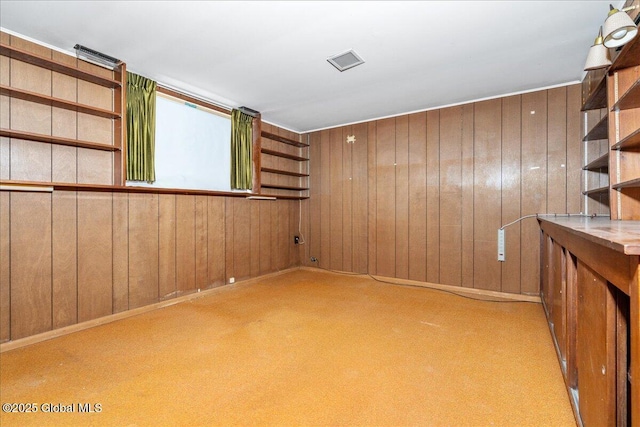 carpeted spare room featuring wooden walls and visible vents