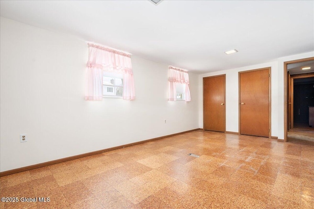 unfurnished bedroom with tile patterned floors, baseboards, and two closets