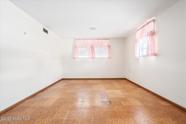 empty room with tile patterned floors, visible vents, and baseboards