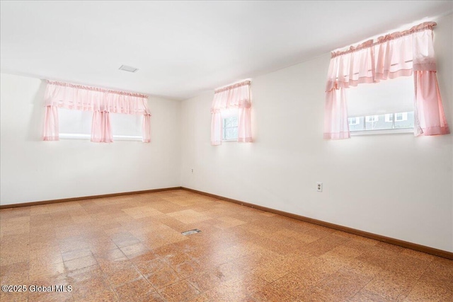 spare room with tile patterned floors, visible vents, and baseboards