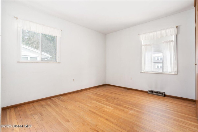 spare room with baseboards, visible vents, and light wood finished floors