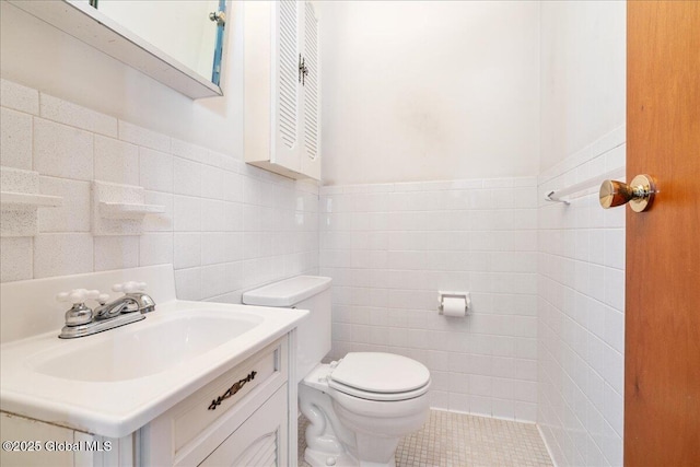 half bathroom with a wainscoted wall, vanity, toilet, and tile walls