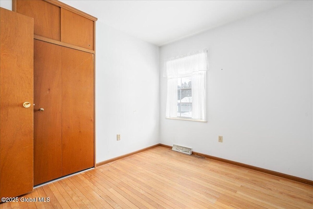 unfurnished bedroom with visible vents, baseboards, light wood-style floors, and a closet