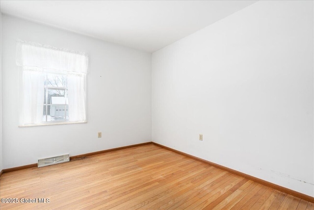 empty room featuring visible vents, light wood-type flooring, and baseboards