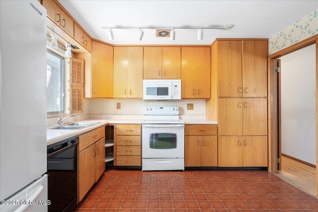 kitchen with a sink, white appliances, dark tile patterned flooring, and light countertops