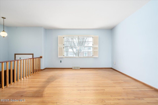 empty room featuring light wood-type flooring, baseboards, and visible vents