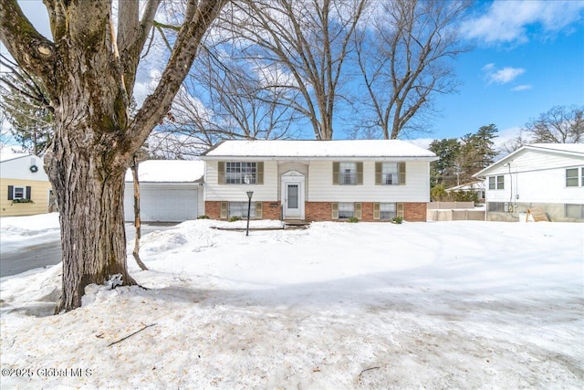 raised ranch featuring a detached garage and brick siding