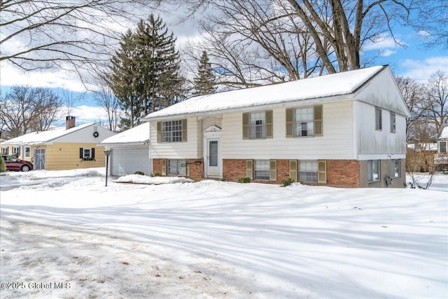 bi-level home featuring a detached garage and brick siding