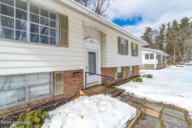 snow covered property entrance with brick siding