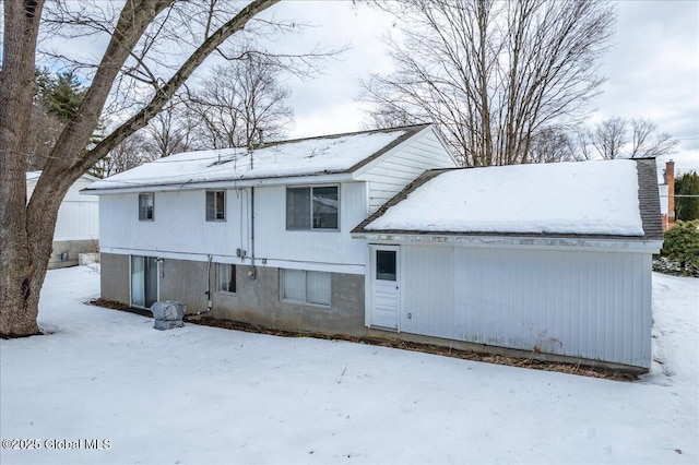 snow covered rear of property featuring a chimney