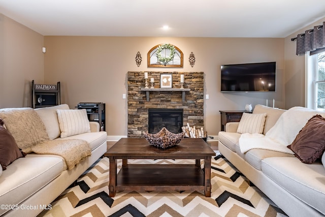 living room featuring a stone fireplace and wood finished floors