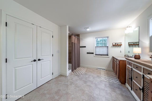 bathroom with a shower with shower curtain, vanity, visible vents, and baseboards