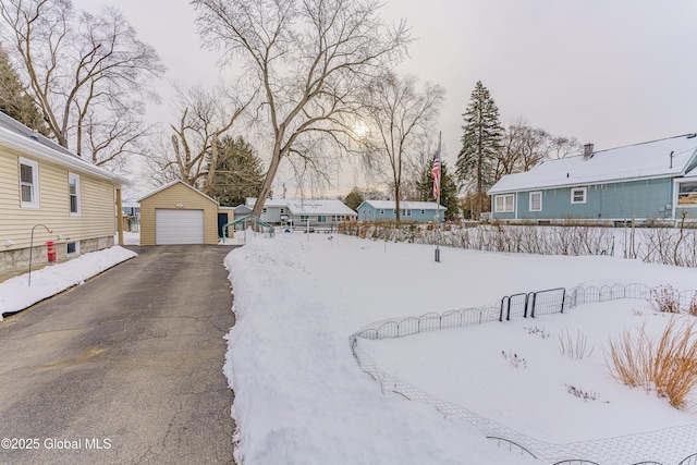 yard layered in snow with an outdoor structure and a garage