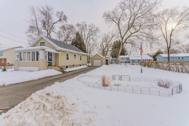 yard layered in snow with a garage, an outbuilding, and a porch