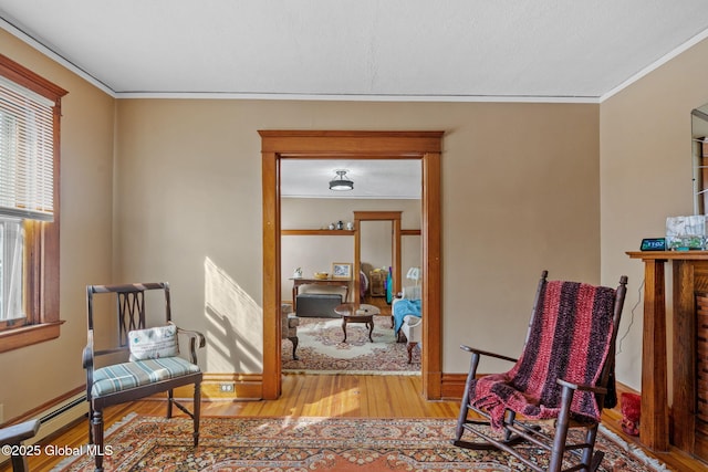 living area featuring light wood-style flooring, ornamental molding, and baseboards