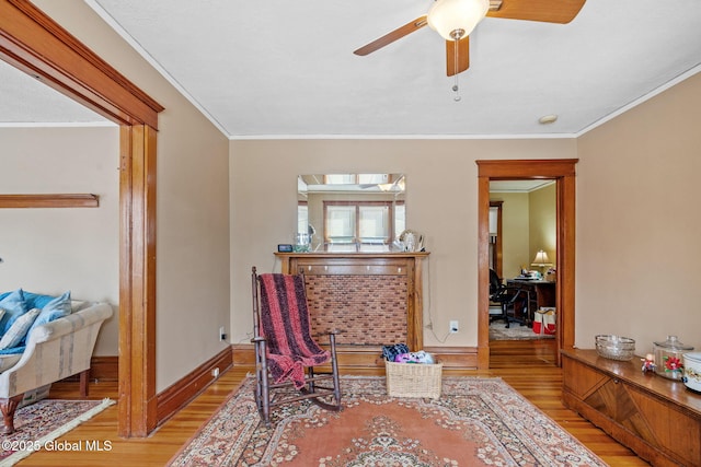 sitting room with light wood finished floors, ceiling fan, baseboards, and crown molding