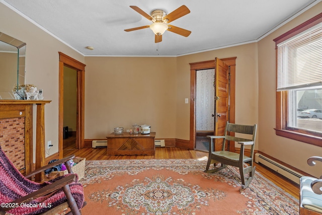 sitting room with a baseboard heating unit, ornamental molding, baseboard heating, and light wood-type flooring