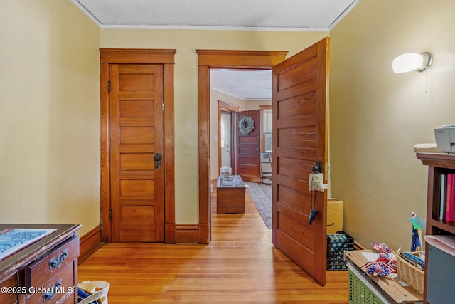 hall with baseboards, light wood-type flooring, and crown molding