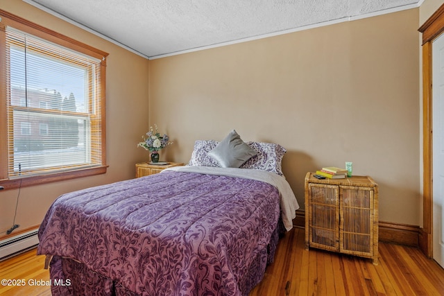 bedroom featuring a textured ceiling, a baseboard radiator, wood-type flooring, and baseboards