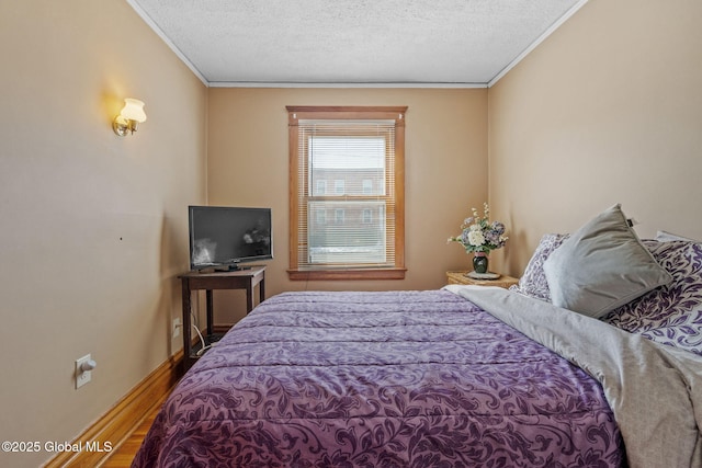 bedroom with a textured ceiling, baseboards, wood finished floors, and crown molding