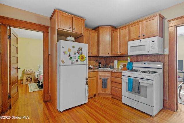 kitchen featuring white appliances, light countertops, a sink, and light wood-style flooring