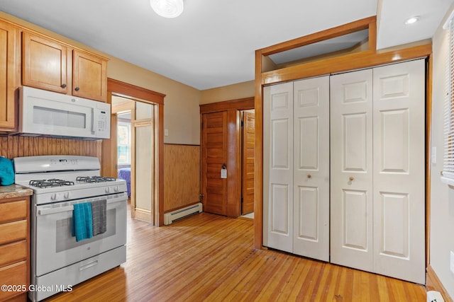 kitchen with a baseboard heating unit, white appliances, light countertops, light wood-type flooring, and wainscoting