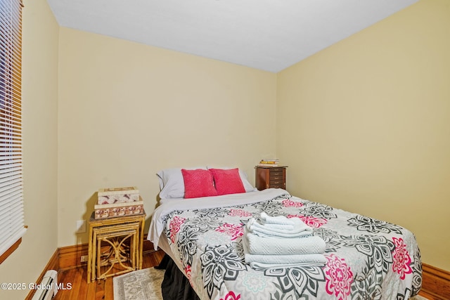 bedroom featuring a baseboard radiator, baseboards, and wood finished floors