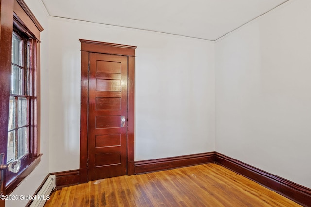 empty room featuring baseboards, baseboard heating, and hardwood / wood-style flooring