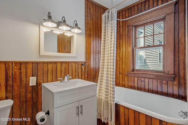 full bathroom with toilet, wooden walls, and vanity