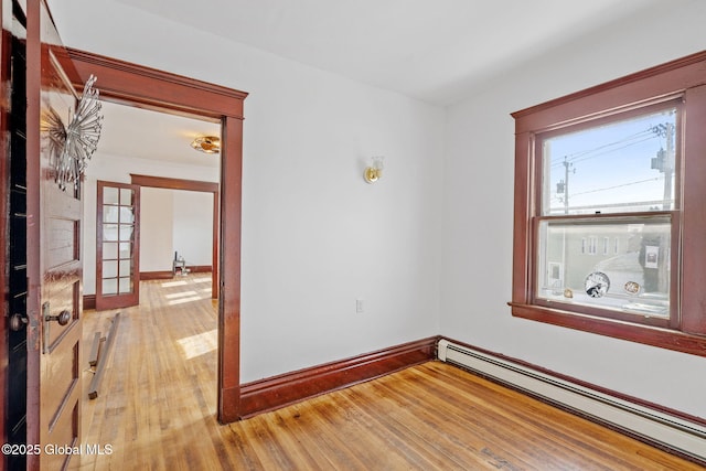 empty room featuring a baseboard radiator, french doors, baseboards, and hardwood / wood-style floors