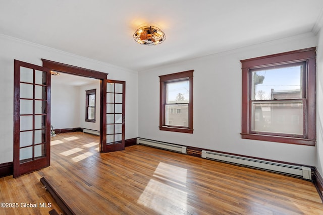 spare room featuring a baseboard heating unit, wood finished floors, baseboards, french doors, and ornamental molding