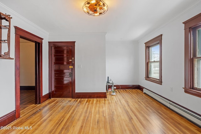 spare room with baseboards, a baseboard radiator, ornamental molding, and wood finished floors