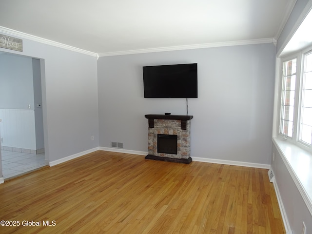 unfurnished living room with a stone fireplace, visible vents, baseboards, ornamental molding, and light wood-type flooring