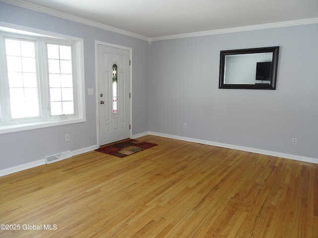 foyer entrance with visible vents, ornamental molding, light wood-style flooring, and baseboards