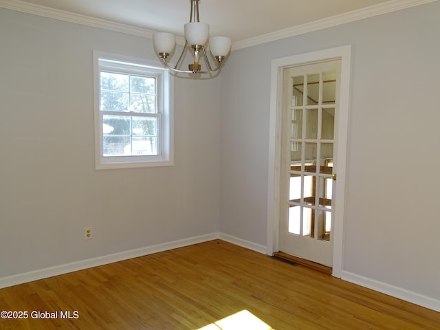 spare room featuring crown molding, baseboards, a chandelier, and light wood-style floors