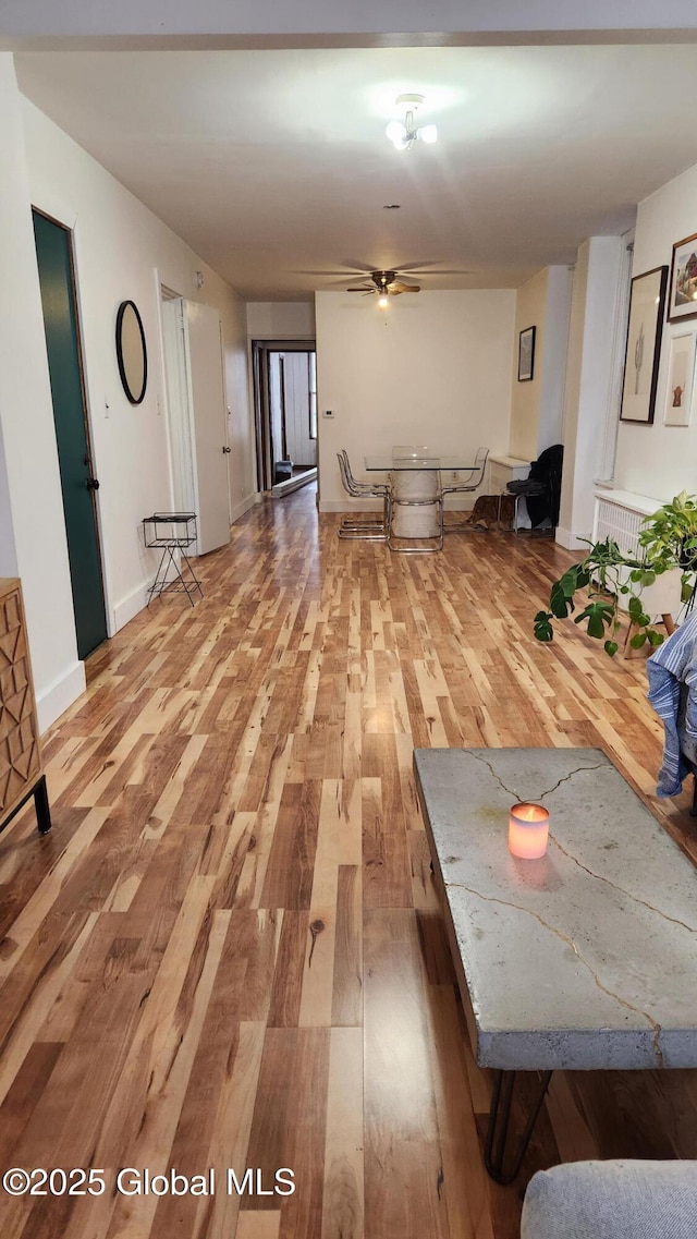 unfurnished living room featuring wood finished floors, a ceiling fan, and baseboards