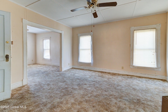 carpeted empty room with baseboards, ornamental molding, and a ceiling fan