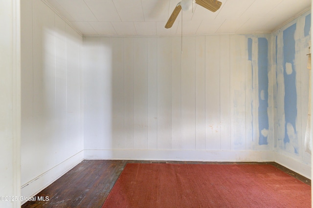 unfurnished room featuring baseboards, dark wood finished floors, and a ceiling fan