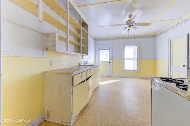 kitchen featuring white gas stove, light floors, light countertops, a ceiling fan, and a sink