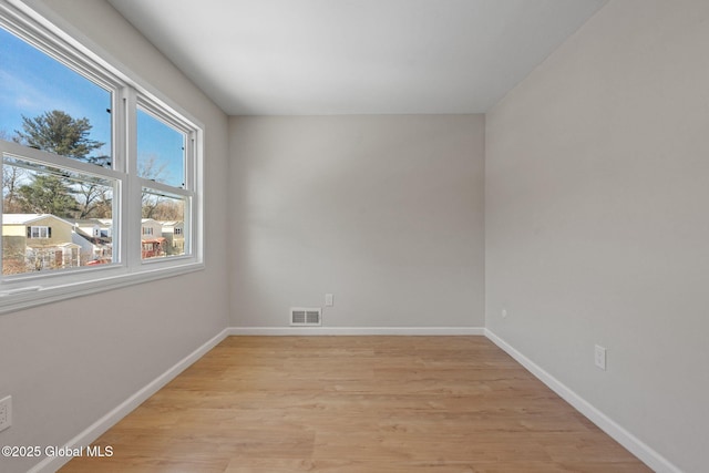 spare room with light wood-type flooring, baseboards, and visible vents