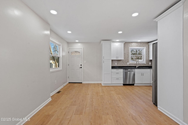 kitchen with dishwasher, dark countertops, white cabinetry, and decorative backsplash