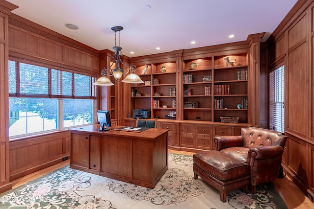 office with built in shelves, wood walls, and light wood-type flooring