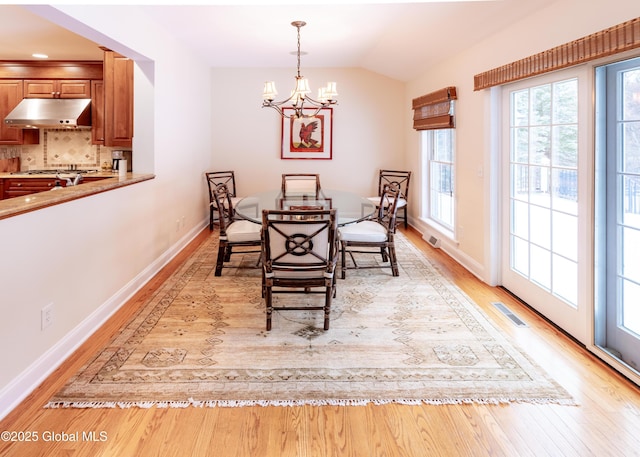 dining area with lofted ceiling, light wood-style flooring, visible vents, and baseboards