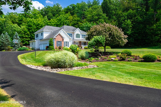 view of front of house featuring an attached garage, a front lawn, aphalt driveway, and brick siding