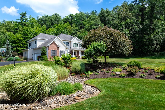 view of front of house featuring driveway, brick siding, and a front yard